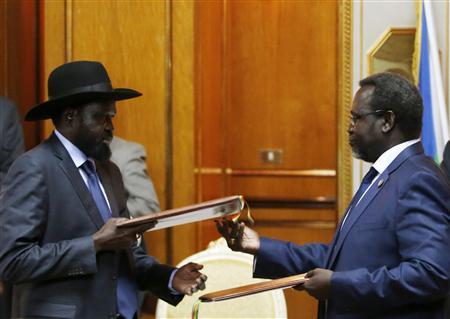 South Sudan's rebel leader Riek Machar (R) and South Sudan's President Salva Kiir (L) exchange signed peace agreement documents in Addis Ababa May 9, 2014. REUTERS/Goran Tomasevic