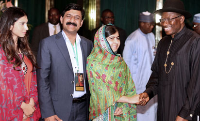 Pakistani education activist Malala Yousafzai (L) watches on July 14, 2014 Nigerian President Goodluck Jonathan look at a book at the State House in Abuja. Malala on July 14 urged Jonathan to meet with parents of the schoolgirls kidnapped three months ago by Boko Haram. Malala, who survived a Taliban assassination attempt in 2012 and has become a champion for access to schooling, was in Abuja on her 17th birthday to mark the somber anniversary of Boko Haram’s April 14 abduction of 276 girls from a secondary school in the northeast Nigerian city of Chibok. AFP PHOTO -