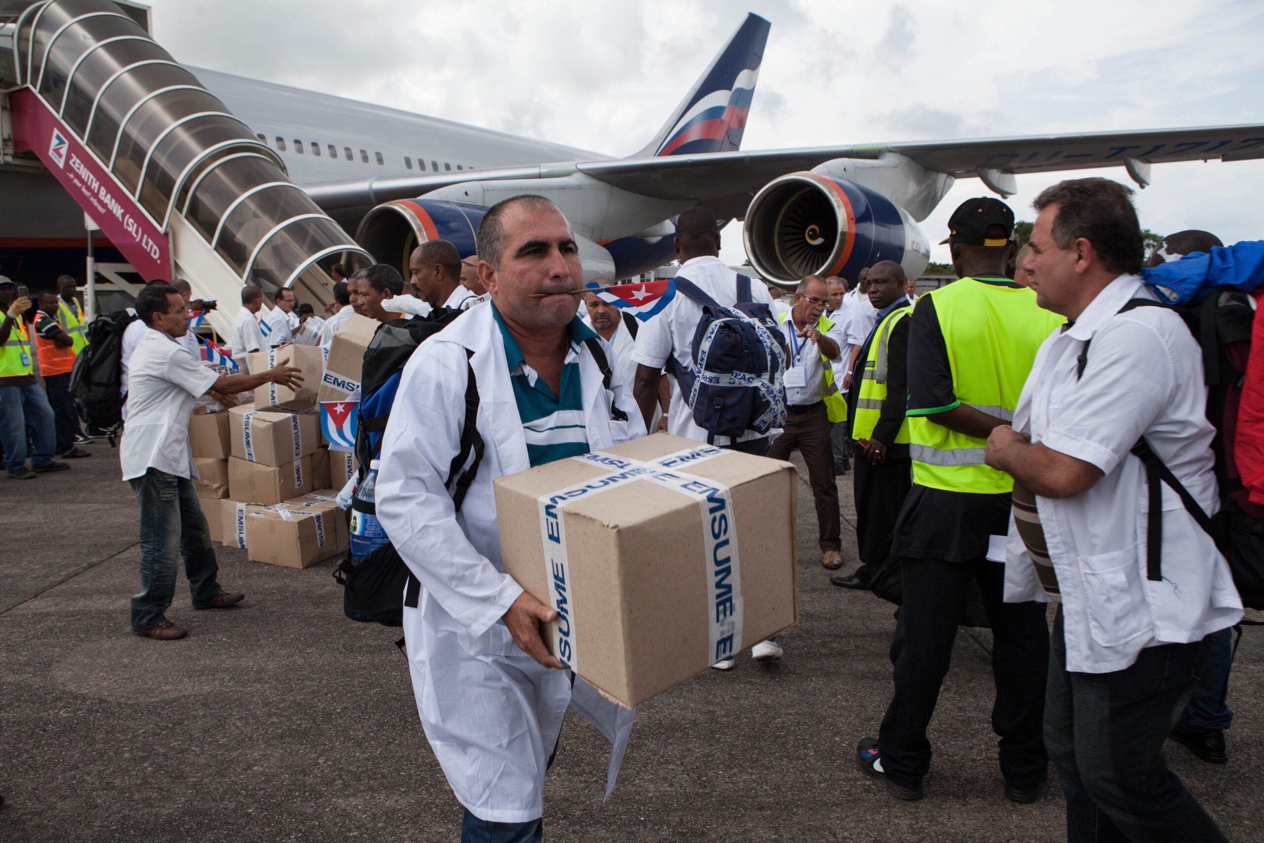 The first members of a team of 165 Cuban doctors and health workers unload boxes of medicines and medical material from a plane upon their arrival at Freetown's airport to help the fight against Ebola in Sierra Leone on Thursday. | AFP-JIJI