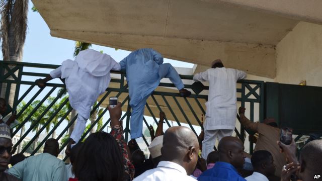 Unidentified lawmakers scale the parliament gate, in Abuja, Nigeria. Nov. 20, 2014.