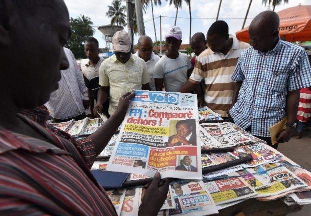 A man looks at a newspaper bearing headlines on the situation in Burkina Faso and reading ''Compaore out!" on November 3, 2014 in Abidjan (AFP Photo/Sia Kambou)
