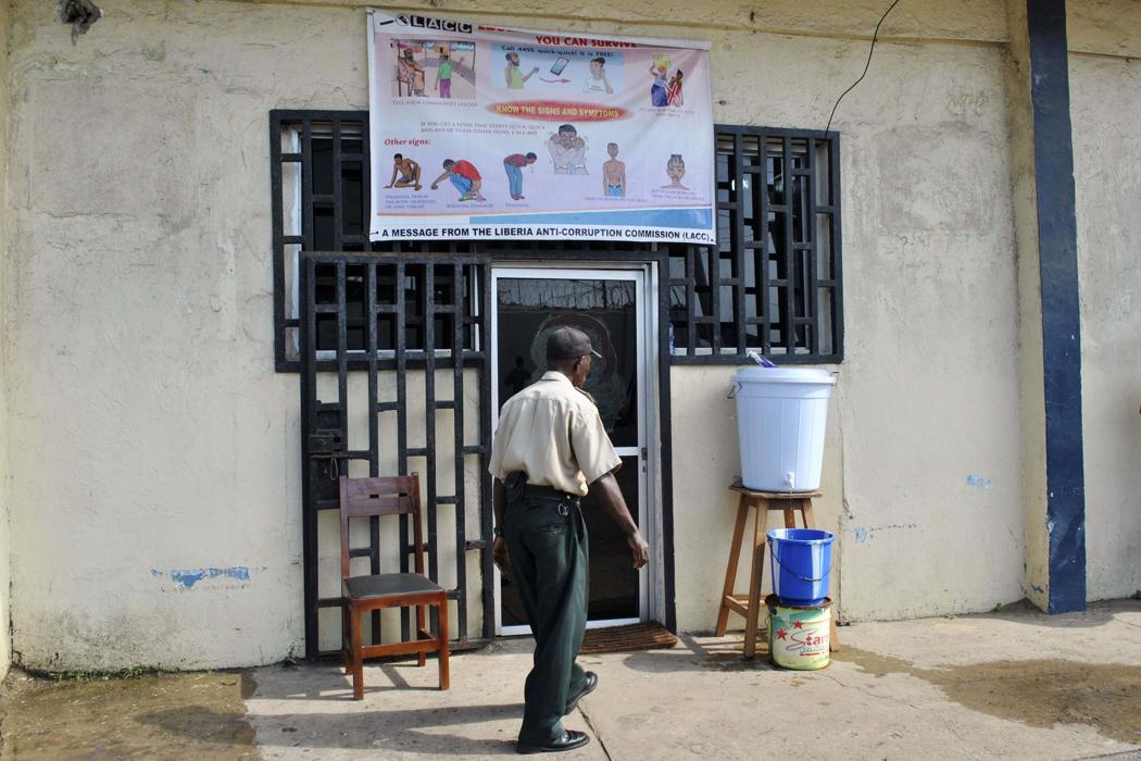 A security guard walks in front of a hand-washing facility at the entrance of a Liberian anti-corruption commission in Monrovia December 9, 2014. (REUTERS/James Giahyue)