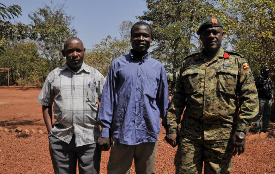 In this photo taken Friday, Jan. 16, 2015 and released by the Uganda People's Defence Force (UPDF), a man said by the UPDF to be the wanted Lord's Resistance Army (LRA) commander Dominic Ongwen, center, stands with Ugandan Contingent Commander to the African Union Regional Task Force Col Michael Kabango, right, and another unidentified man, left, prior to being handed over by the UPDF to the African Union Regional Task Force who later handed him over to Central African Republic authorities, in the Central African Republic. Central African Republic's Seleka rebels, who once overthrew the government, say they're entitled to a $5 million reward from the U.S. government because they say they captured and handed over the wanted international war crimes suspect Dominic Ongwen to American forces. (AP Photo/Uganda People's Defence Force, Mugisha Richard)