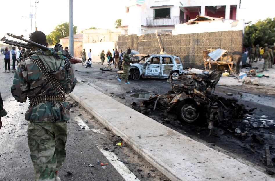 A Somalis soldier patrols near the wreckage of cars after a suicide car bomb blast on January 4, 2015 in Mogadishu (AFP Photo/Abdifitah Hashi Nor)