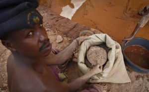 In this photo taken Wednesday, Aug. 19, 2015, a Ugandan gold miner scoops powdered ore to be washed to separate the dirt from the gold, in the Mubende district west of the capital Kampala, in Uganda. The gold rush is on in a big way in the Ugandan district of Mubende, with tens of thousands of people making their livelihood from it. (AP Photo/Stephen Wandera)