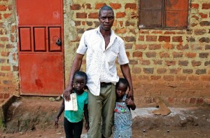 Isha Ssemata, the father of Ugandan boy Mohammad Luwasi, who Ugandan authorities claim has been trafficked to the US, poses at his home in Uganda's Sonde village with his other children Latifa and Rahmah (AFP Photo/Amy Fallon)