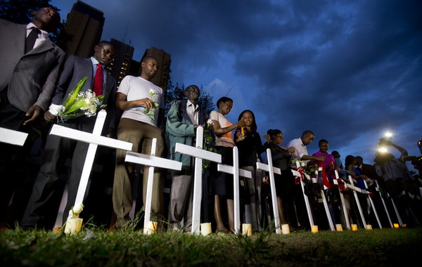 Kenyans light candles next to a white wooden cross for each of the victims of the Garissa attack, during a vigil at Uhuru Park in Nairobi, Kenya Tuesday, April 7, 2015. Students and other Kenyans gathered at dusk to honor and remember the victims, lighting candles, holding flowers, reading their names aloud, and erecting a white wooden cross for each of those who were killed in the Garissa University College attack.