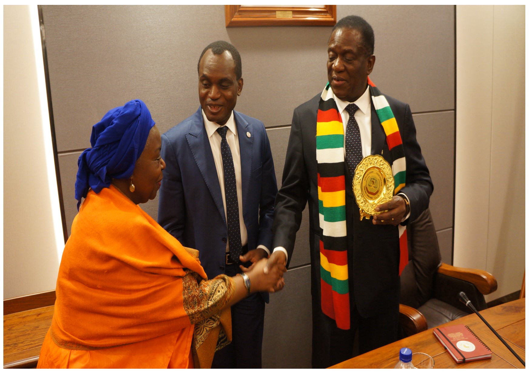 Zimbabwe's President Mnangawa greets a Judge of the Court Justice Hon Justice Tujilane Rose Chizumila after receiving a plaque from the Court's President Hon Justice Sylvain Oré (m).