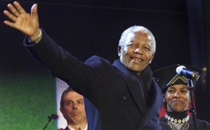 Nelson Mandela waves from the stage with British Prime Minister Tony Blair (L) and South African High Commissioner Cheryl Carolus at Trafalgar Square during the South African democracy concert, in this April 29, 2001 file photo. CREDIT: REUTERS/FILES