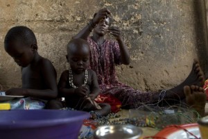 A Ugandan woman makes paper beads with the help of her children on March 1, 2008, at their home in the Namuwungo slum in Kampala (AFP Photo/Walter Astrada)