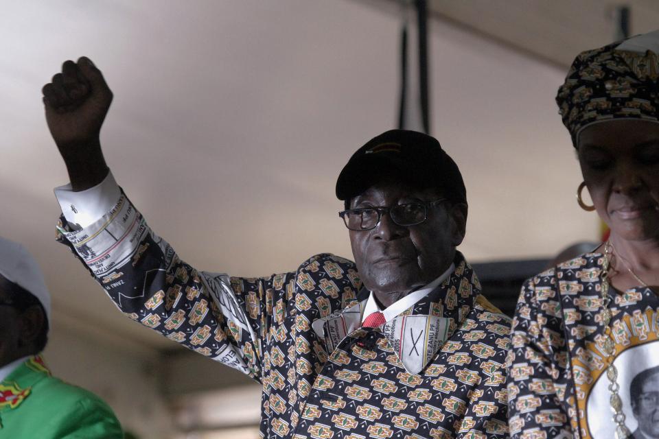 Zimbabwean President Robert Mugabe gestures as he greets the crowd upon arrival on the last day of the Zanu PF 6th National Congress, in Harare, Sat, Dec. 6, 2014. Zimbabwe's vice president was a rebel commander known as "Spill Blood" during the war against white rulers and, at the age of 25, became the youngest Cabinet minister after independence. Now she is a political pariah, accused of plotting the downfall of President Robert Mugabe with the help of nocturnal sorcery. (AP Photo/Tsvangirayi Mukwazhi)