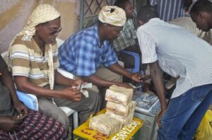 In this photo taken Sunday, Feb. 16, 2014, a customer of Dahabshiil, Somalia's largest remittance company, exchanges his US dollar bills for Somali shillings outside the company's headquarters in Mogadishu, Somalia. Money transfer services have operated for years, but they are now under intense scrutiny as many countries, especially the U.S. and U.K., have accused the agencies of helping fund Islamic extremist terrorist groups. That concern has forced some international banks to terminate business with them — anti-terror laws hold banks responsible if they transfer money to criminal or terror elements. (AP Photo/Farah Abdi Warsameh) 