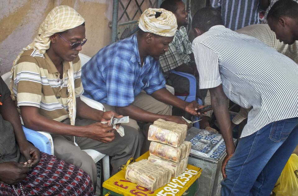 In this photo taken Sunday, Feb. 16, 2014, a customer of Dahabshiil, Somalia's largest remittance company, exchanges his US dollar bills for Somali shillings outside the company's headquarters in Mogadishu, Somalia. Money transfer services have operated for years, but they are now under intense scrutiny as many countries, especially the U.S. and U.K., have accused the agencies of helping fund Islamic extremist terrorist groups. That concern has forced some international banks to terminate business with them — anti-terror laws hold banks responsible if they transfer money to criminal or terror elements. (AP Photo/Farah Abdi Warsameh)