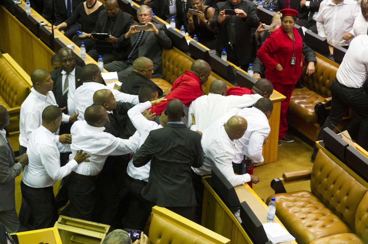 Members of Julius Malema's Economic Freedom Fighters (EFF) (in red) clash with security officials after being ordered out of the chamber during President Jacob Zuma's State of the Nation address in parliament in Cape Town February 12, 2015. The opening of South Africa's parliament descended into chaos on Thursday as security officers fought with far-left Economic Freedom Fighters (EFF) lawmakers after they disrupted President Jacob Zuma's speech. REUTERS/Roger Bosch/Pool (SOUTH AFRICA - Tags: POLITICS CIVIL UNREST)