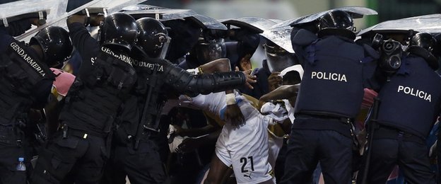 Riot police shield Ghana players as they try to come off at half-time at the Estadio de Malabo