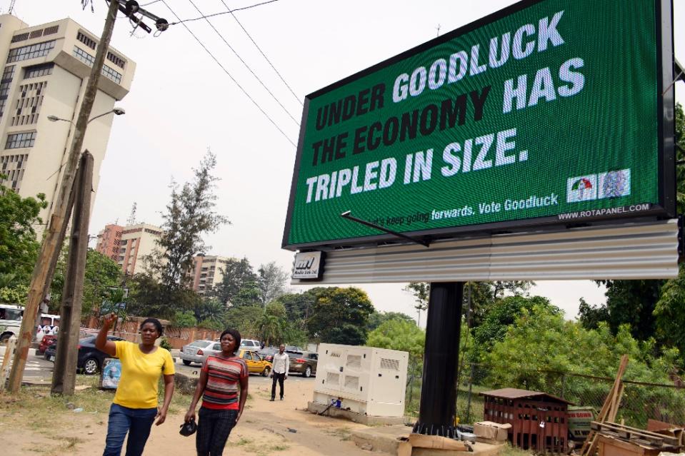 Two women walk past a campaign billboard of Nigeria's President Goodluck Jonathan and candidate for his re-election for the ruling People Democratic Party (PDP), in the Ikoyi district of Lagos, on February 24, 2015 (AFP Photo/Pius Utomi Ekpei)