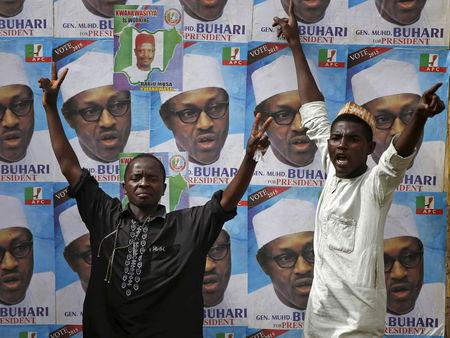 Supporters of presidential candidate Muhammadu Buhari gesture in front of his election posters in Kano March 27, 2015. REUTERS/Goran Tomasevic