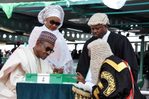 Nigerian President Mohammadu Buhari (L) sits beside his wife Aisha, as he signs a document after taking an oath during his inauguration in Abuja, on May 29, 2015 (AFP Photo/)