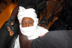 Security personnel surround former Chadian dictator Hissene Habre inside the court in Dakar, Senegal, Monday, July 20, 2015. The trial of former Chadian dictator Hissene Habre, accused of overseeing the deaths of thousands, had a chaotic beginning Monday as security forces ushered the ex-leader into and then out of the Senegal courtroom amid protests by his supporters.(AP Photo/Sophiane Bengeloun)