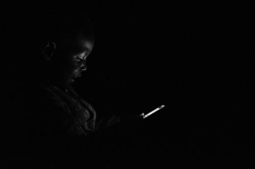 Technology Category and Grand Prize Winner: The Digital Age: Everyone from rural to urban areas in Uganda can now afford to have a mobile phone. Photographer’s 1-year-old son uses a mobile phone during a blackout. Photographer: Mohsen Taha, 28 years old, Uganda.