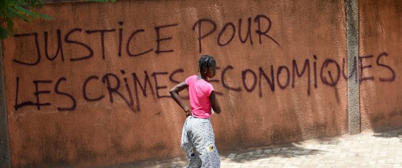 A woman walks past a wall with graffiti reading "Justice for the economic crimes" in Ouagadougou on October 1, 2015. General Gilbert Diendere, the leader of Burkina Faso's short-lived coup, was in police custody on October 1, a security source told AFP.  AFP PHOTO / SIA KAMBOU        (Photo credit should read SIA KAMBOU/AFP/Getty Images)