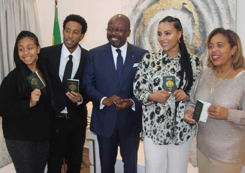 Ludacris and family pose with Gabonese official brandishing their passports